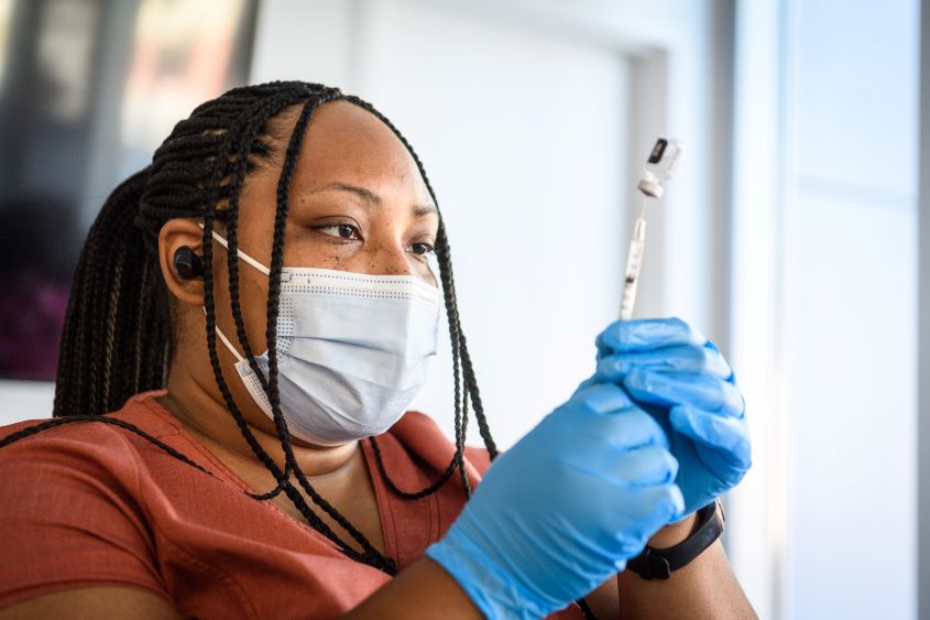 Nurse holding a needle and vaccine vial.