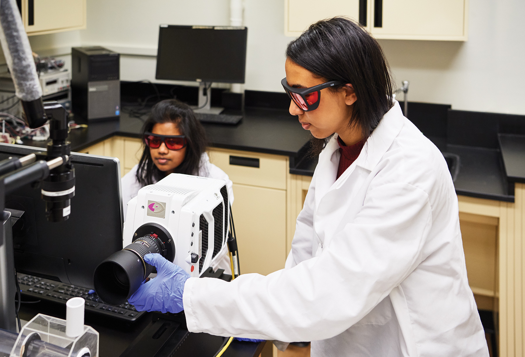 two female students in lab coats and goggles