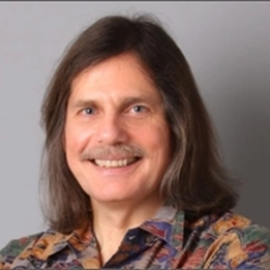 A smiling man with long hair and mustach