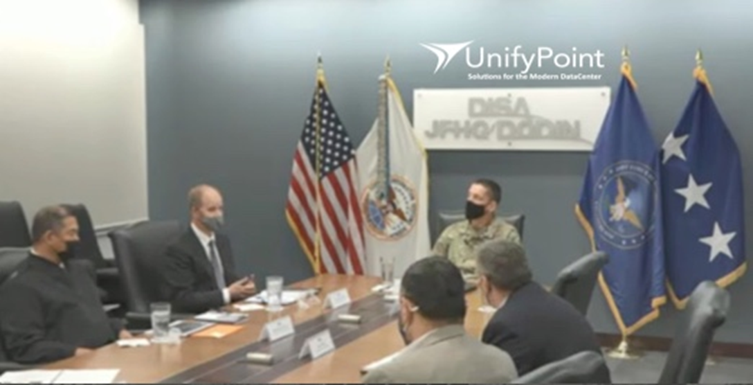 Man dressed in military attire presents to people at a table at the Department of Defense