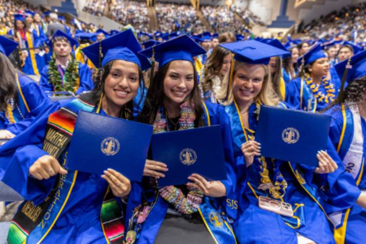 Female SJSU graduates holding their diplomas in commencement regalia