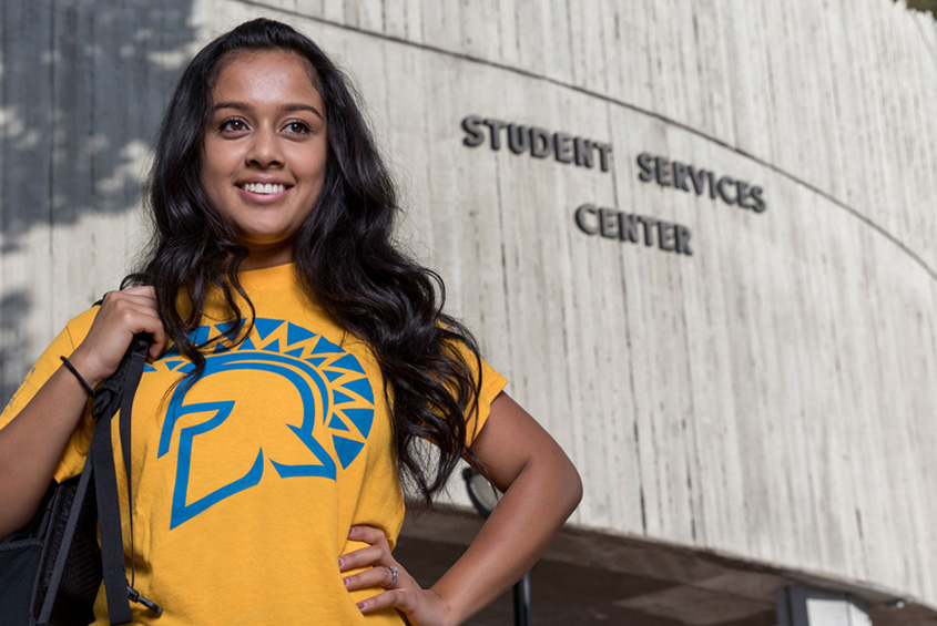 A student standing in front of the services building.