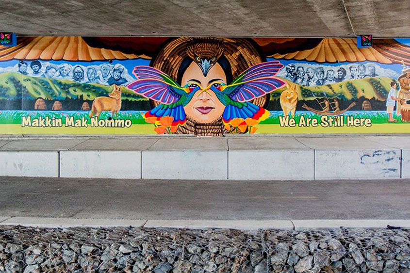 A colorful mural under a bridge.