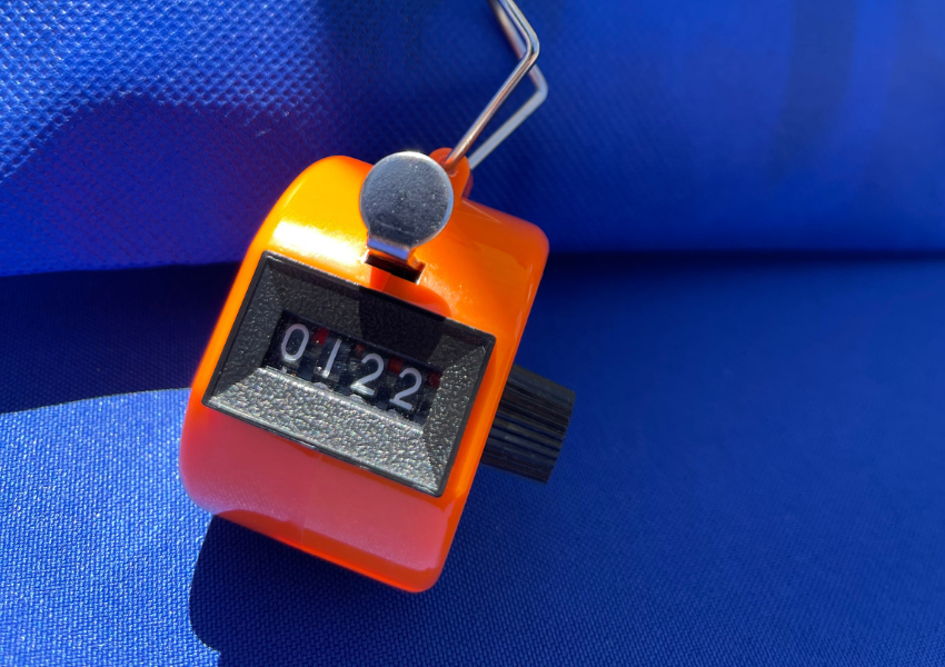 Orange clicker counter on a blue tablecloth background 
