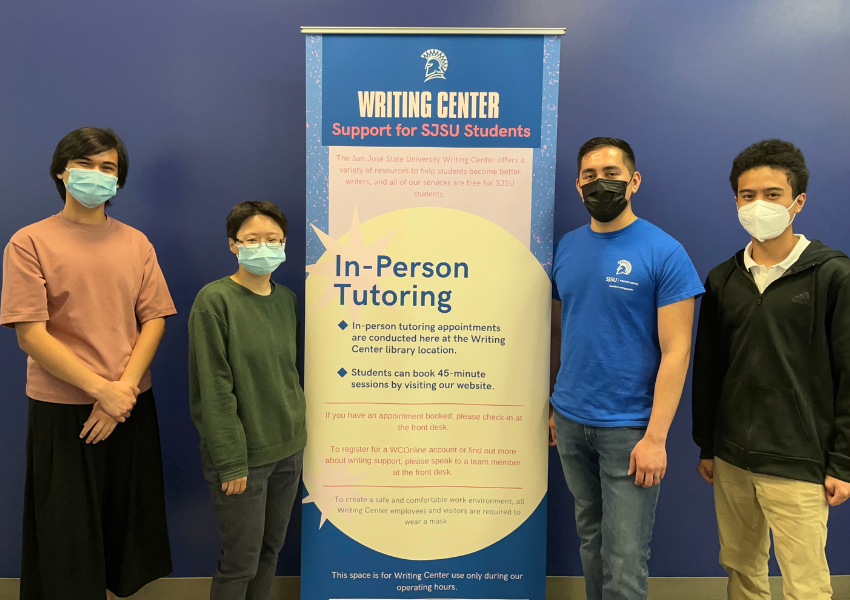 Student employees wearing masks standing next to the retractable banner